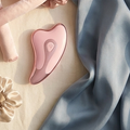 Brand imagery (AI-generated from supplier reference): pink microcurrent gua sha wand on cream linen with dusty-blue silk